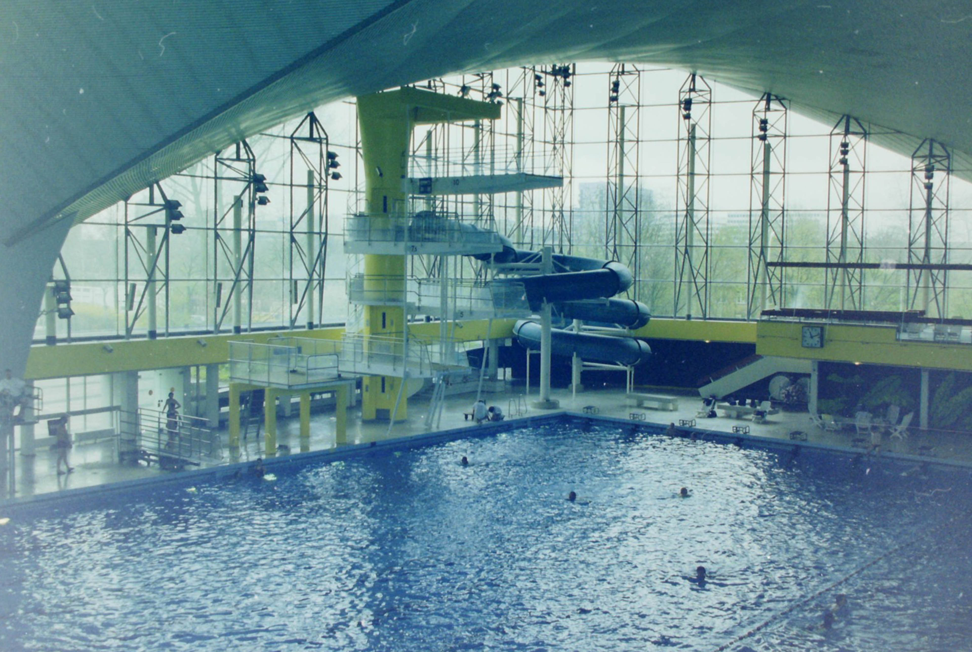 Schwimmbecken mit Sprungturm und Rutsche im Hintergrund