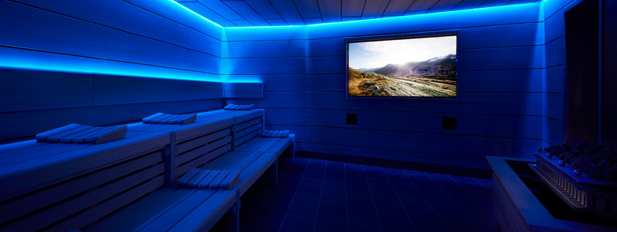Sauna mit blauer Beleuchtung und Bildschirm, auf dem Landschaft gezeigt wird