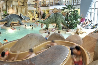 Eine stark benutzte Wasserrutsche führt direkt in das Becken, welches umringt von wasserspeienden, lebensgroßen Dinosauriern ist.