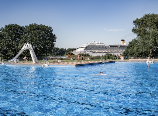 Freibad mit Rutschen und Kreuzfahrtschiff im Hintergrund