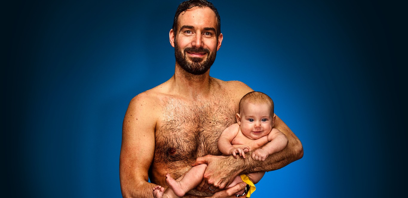 Mann mit Baby auf dem Arm vor blauem Hintergrund