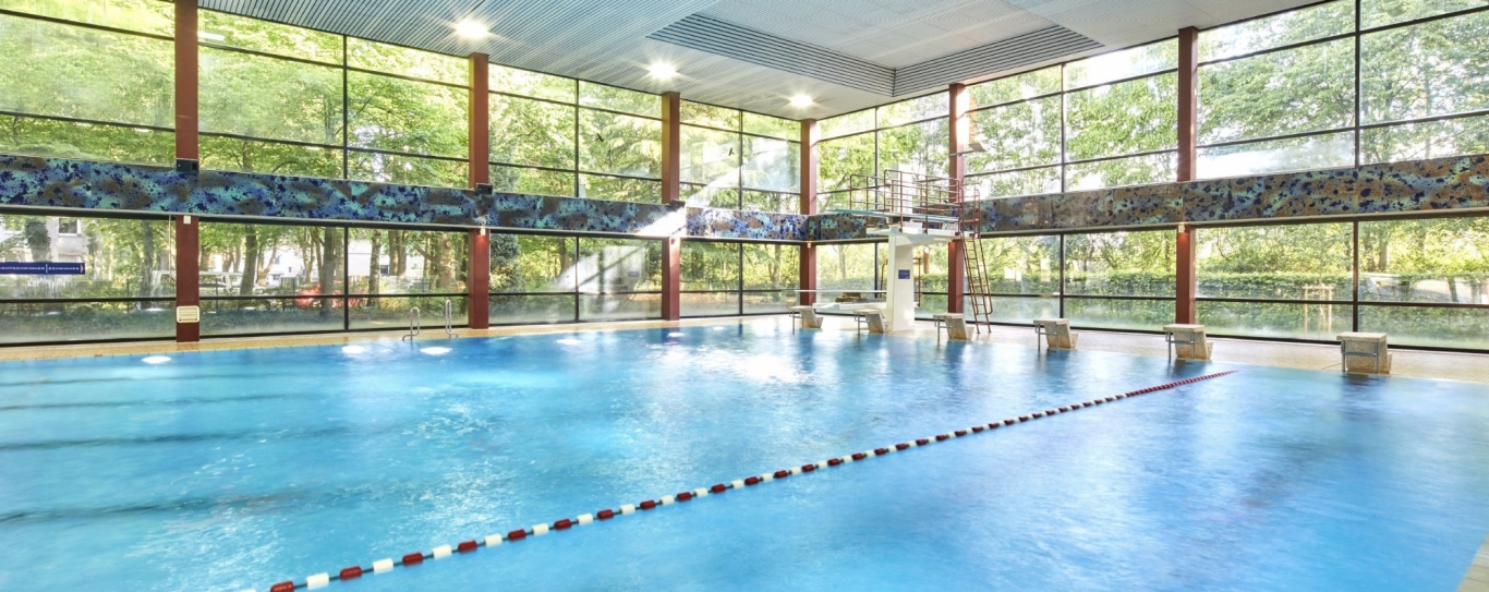 Schwimmbad mit Bahnen, Fensterfront und Lichtern an der Decke