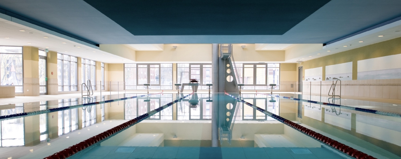 Schwimmbad mit hellen Wänden, Fensterfront und dunkler Decke