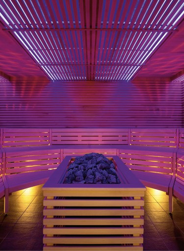 Sauna mit pinkfarbener Beleuchtung und Ofen