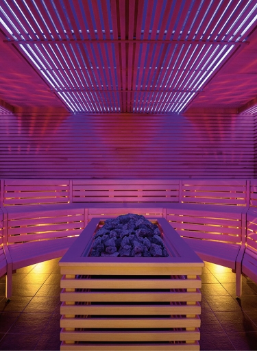 Sauna mit pinkfarbener Beleuchtung und Ofen