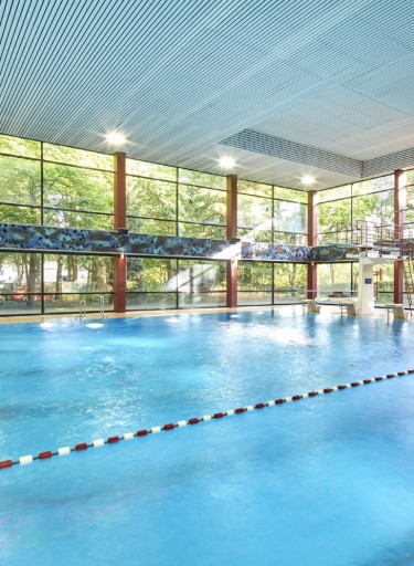 Schwimmbad mit Bahnen, Fensterfront und Lichtern an der Decke