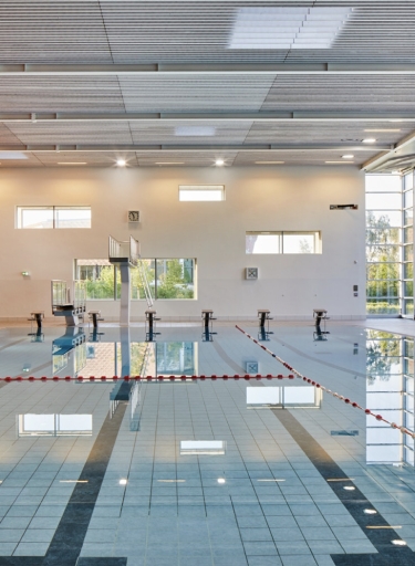 Schwimmbad mit Bahnen, Startblöcken und Fensterfront rechts