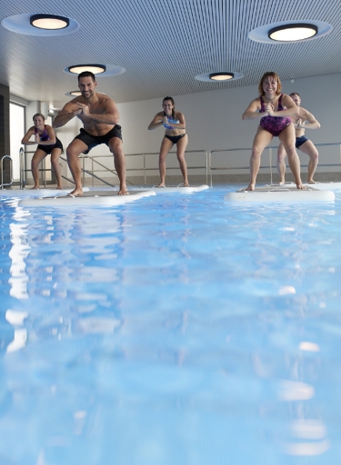 Menschen in Kniebeuge auf Boards auf dem Wasser.