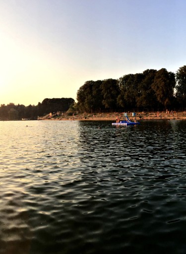 Stadtparksee mit Ufer und Sonnenuntergang.