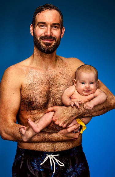 Mann mit Baby auf dem Arm vor blauem Hintergrund