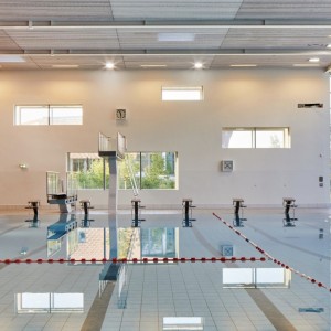 Schwimmbad mit Bahnen, Startblöcken und Fensterfront rechts