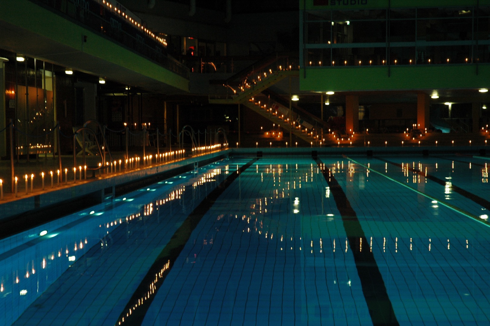 Schwimmbecken im dunkeln und drum herum brennende Kerzen aufgestellt