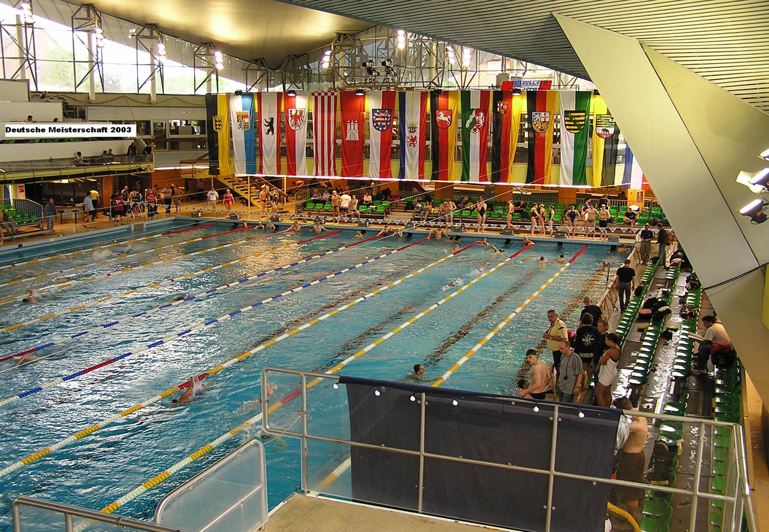 Schwimmbecken voller Schwimmer und Personen die zugucken