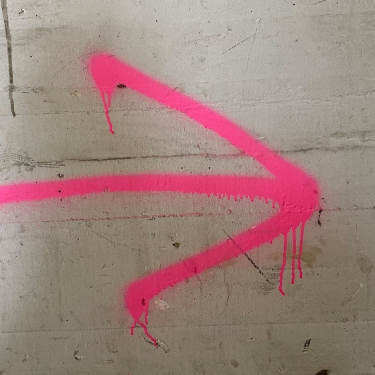 Pinker Pfeil der nach rechts zeigt auf eine Wand gemalt.