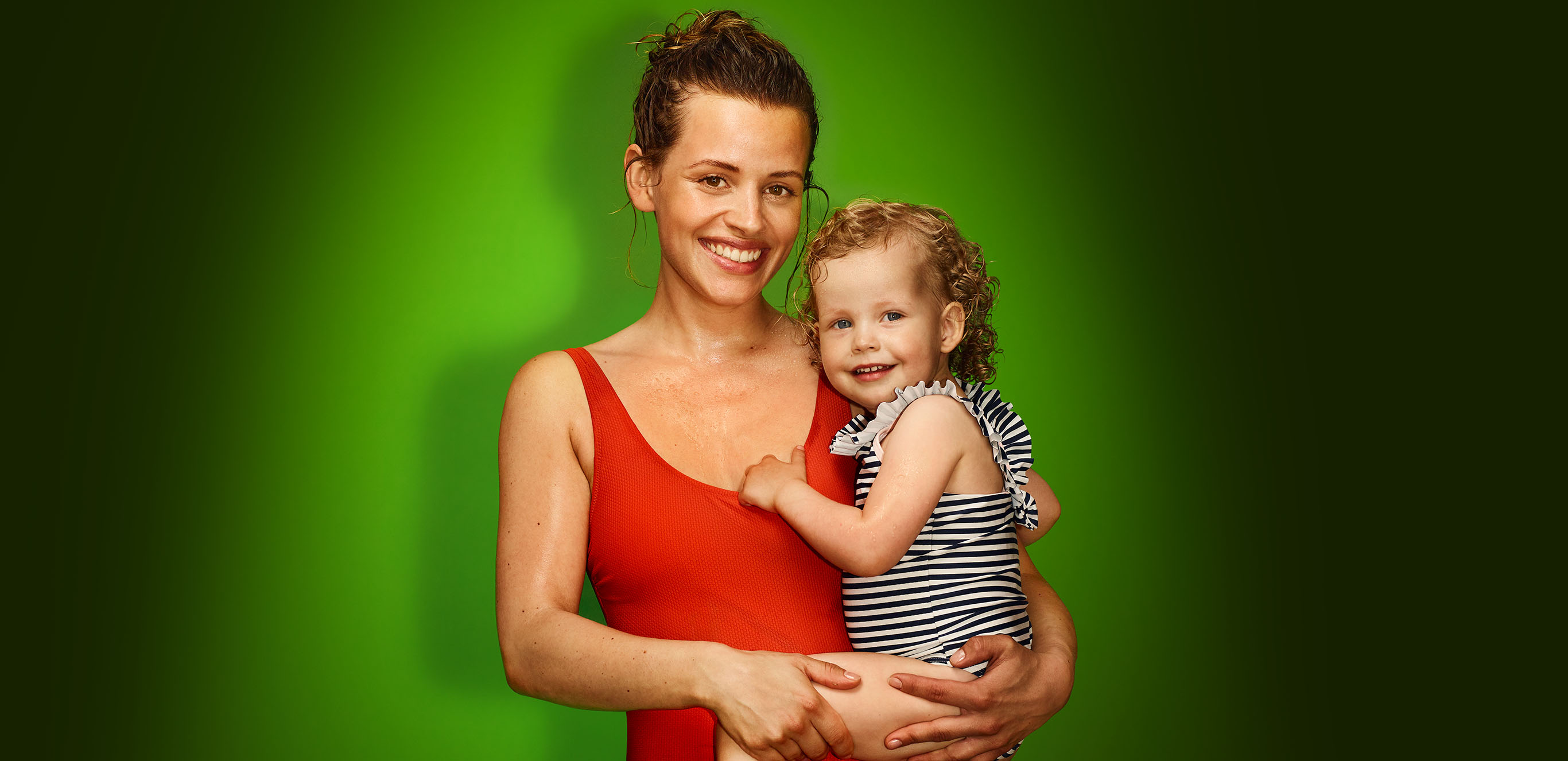 Frau mit Kind auf dem Arm vor grünem Hintergrund