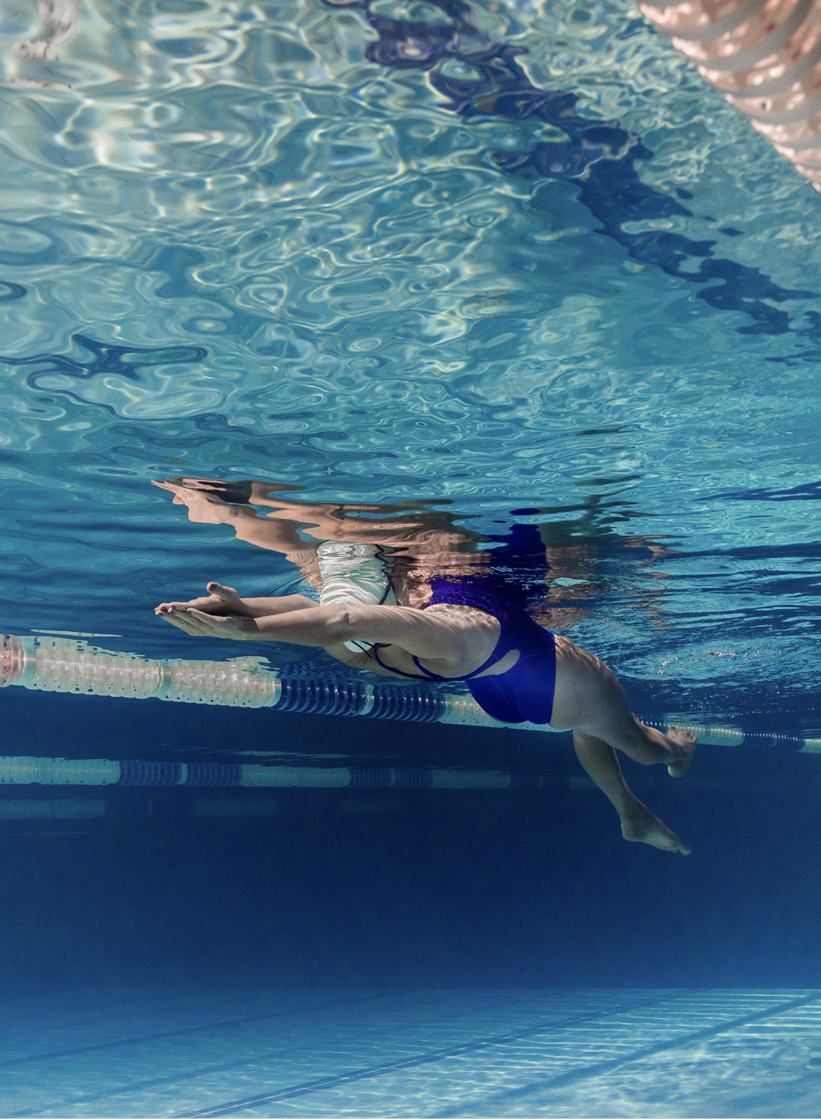 Frau mit blauem Badeanzug gleitet unter Wasser