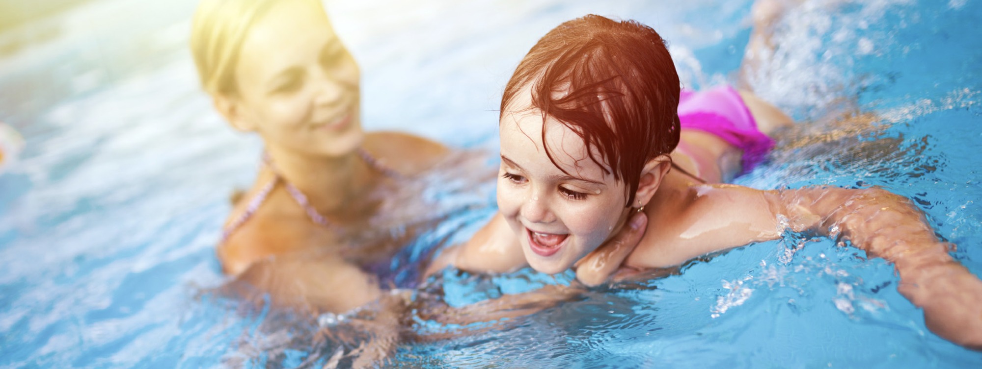 Mutter im Wasser und beaufsichtigt Kind im Wasser.