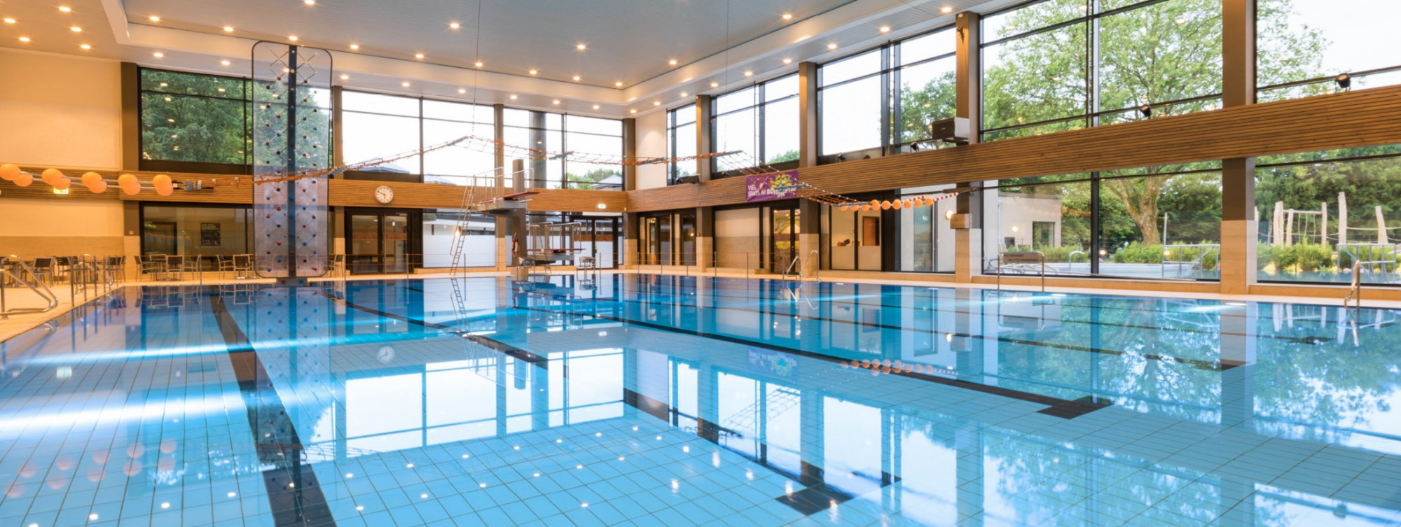 Schwimmbad mit Bahnen, Fensterfront und Lichtern an der Decke