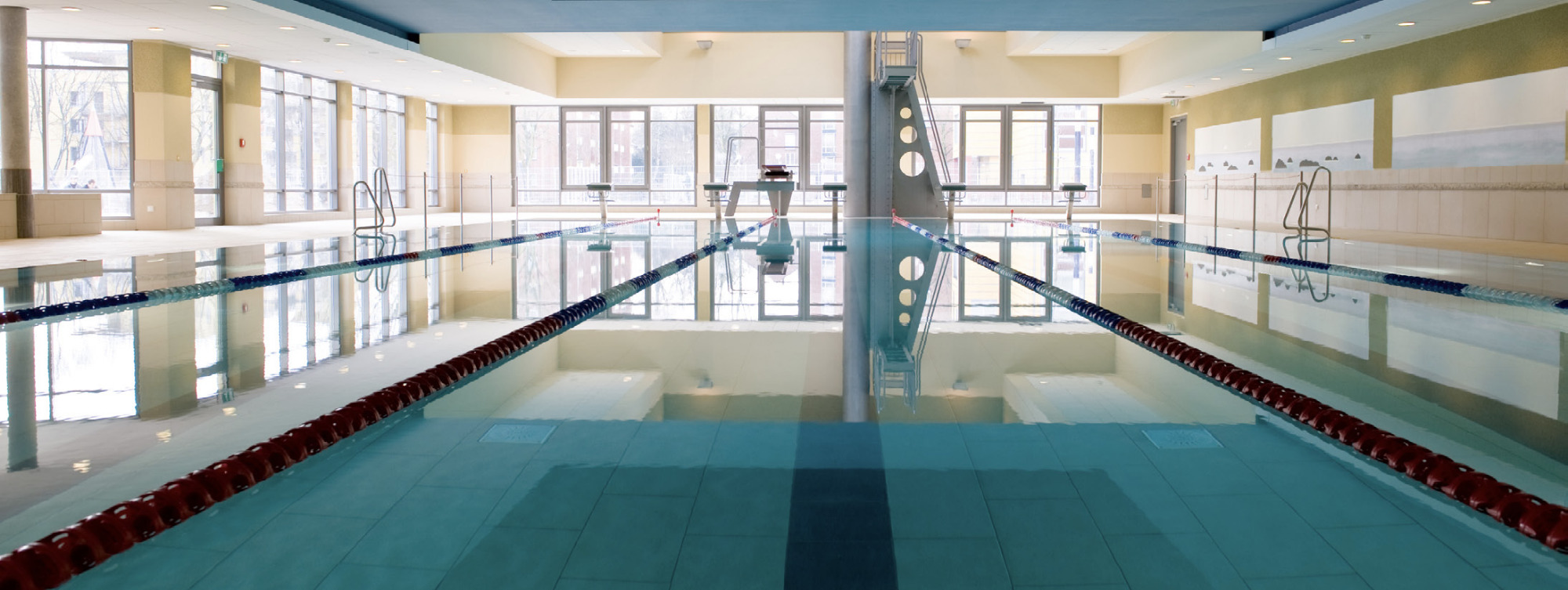 Schwimmbad mit hellen Wänden, Fensterfront und dunkler Decke