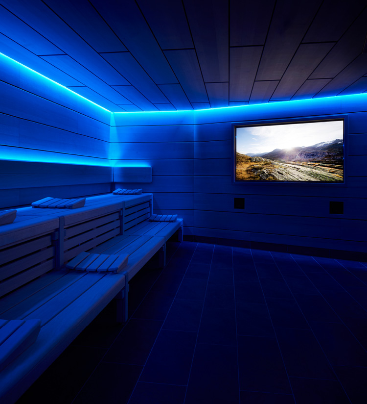 Sauna mit blauer Beleuchtung und Bildschirm, auf dem Landschaft gezeigt wird