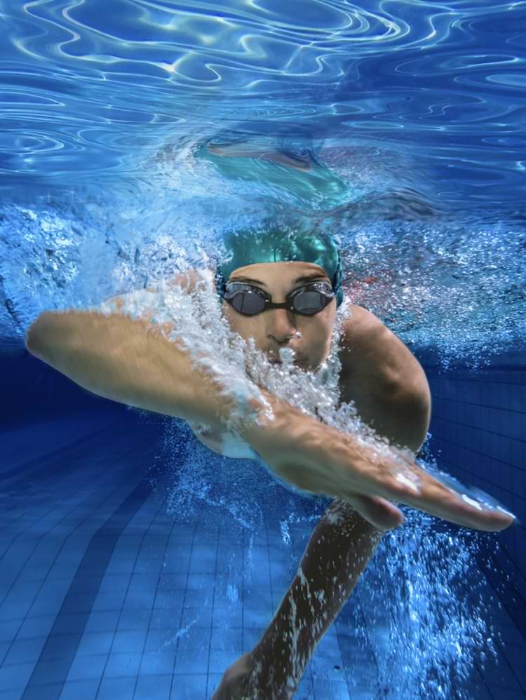 Mann mit grüner Badekappe und Schwimmbrille unter Wasser