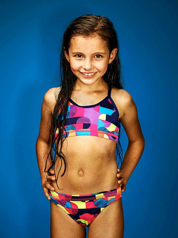 Mädchen mit buntem Bikini vor blauem Hintergrund