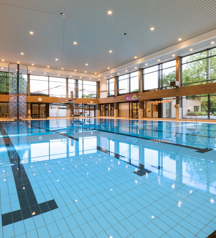 Schwimmbad mit Bahnen, Fensterfront und Lichtern an der Decke