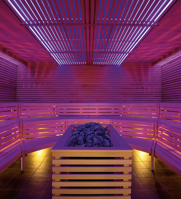 Holzsauna mit Ofen und pinkfarbener Beleuchtung