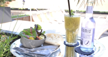 Tablett mit Salat, Saft und Wasser draußen in der Sonne.