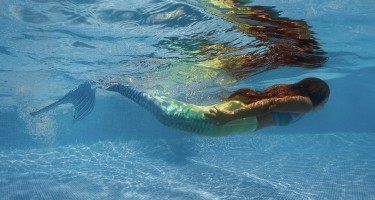 Mädchen mit Meerjungfrauenflosse unter Wasser