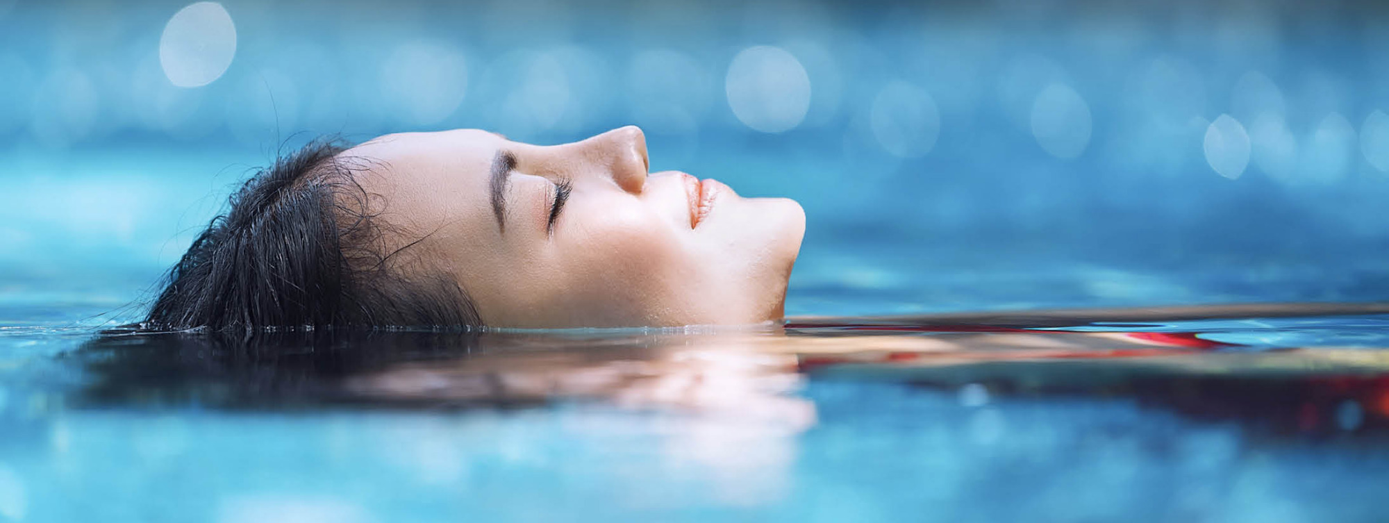 Frau floated entspannt auf dem Rücken im Wasser mit Nahaufnahme von ihrem Gesicht