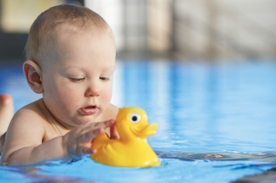 Baby mit Plastikente im Wasser