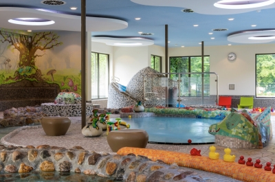 Indoor Kinderspielparadies. Die Kinderbecken sind umrandet mit Steinen, Enten und einem wasserspeiendem Kugelfisch.