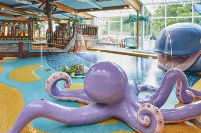 Im Vordergrund ist ein lebensgroße Oktopus mit wasserspuchenden Tentakeln. Im Hintergrund sind ein lebensgroßer Wal, sowie eine Schildkröte und ein Piratenschiff.