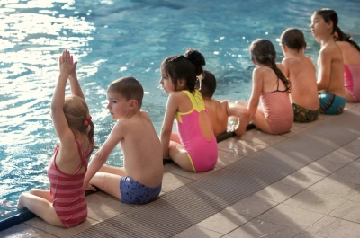 Gruppe Kinder von hinten am Beckenrand, bereit ins Wasser zu springen