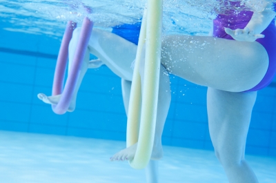 Zwei Frauen mit Schwimmnudeln unter dem Fuß unter Wasser