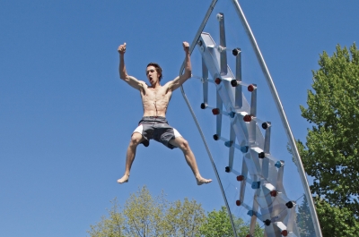 Junge springt von Kletterwand ins Freibadbecken.