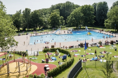 Große Außenanlage des Freibades mit Becken, Liegewiese und Kletterspielplatz.